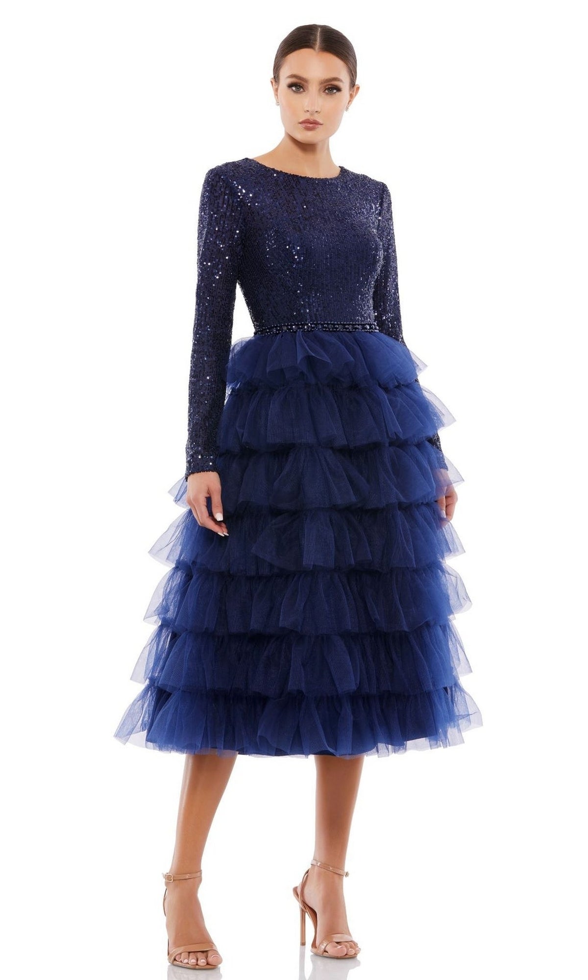 Woman wearing the Mac Duggal 26299 Knee-Length Wedding Guest Dress in navy blue sequins with a layered tulle skirt and strappy nude heels, standing against a plain white background.